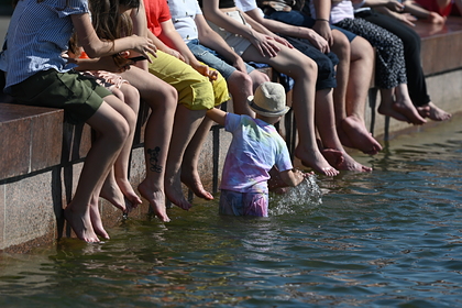 Отдыхающие в жаркую погоду сидят у фонтана на ВДНХ в Москве