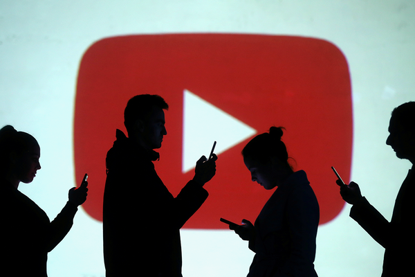 Silhouettes of mobile users are seen next to a screen projection of Youtube logo in this picture illustration taken March 28, 2018.  REUTERS/Dado Ruvic/Illustration